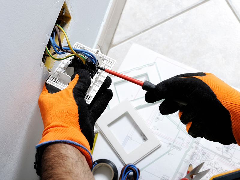 electrician hands close up with protection gloves repairing wall outlet apache junction az
